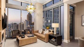 A modern living room with a sofa, coffee table, and a large window offering a city view.