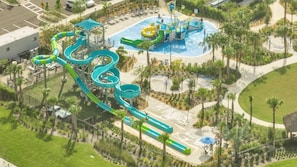 An aerial view of a water park with multiple slides and pools, surrounded by palm trees and a parking area. - Go 31- Champions Gate (Kissimmee)