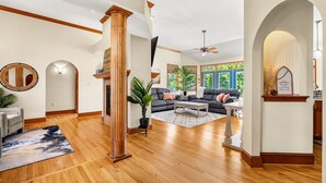 A spacious living room with hardwood flooring, a large fireplace, a sofa set, and a view of greenery outside. - Tranquil Tellico Lakefront Retreat -- Kayaks! Private Dock! (Loudon)