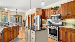 A modern kitchen with wooden cabinets, stainless steel appliances, and pendant lighting. - Tranquil Tellico Lakefront Retreat -- Kayaks! Private Dock! (Loudon)