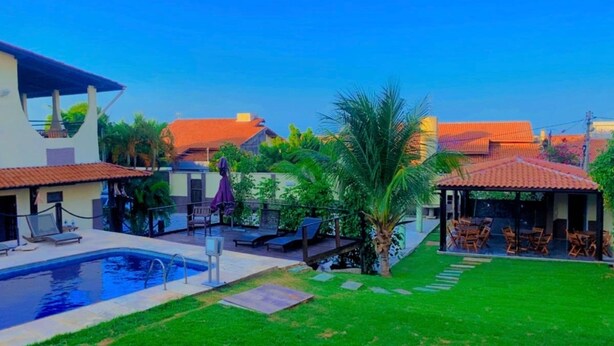 A residential area with a swimming pool, outdoor seating, and a covered patio.