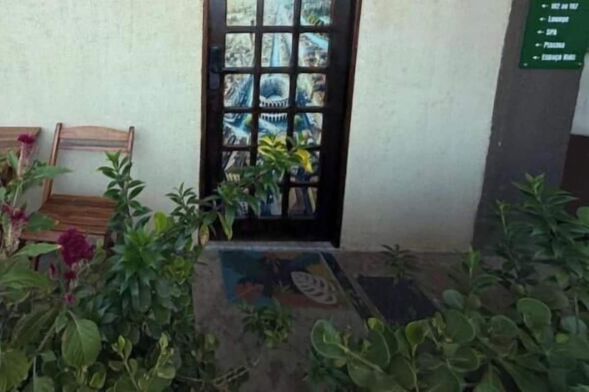 A wooden table and chairs outside a building with a door and plants.
