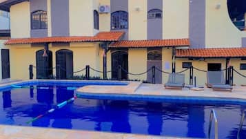 Una piscina al aire libre, sillones reclinables de piscina