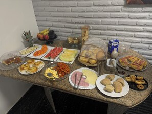A buffet table with various food items including fruits, vegetables, pastries, and meats. - Pousada Vila Italia - Porto das Dunas (Aquiraz)
