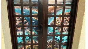 A door with a grid pattern and a view of a coastal town through the grid.