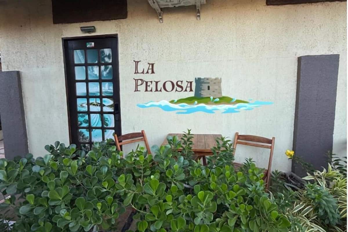 A building with a sign reading 'LA PELOSA' and a small table with chairs in front.