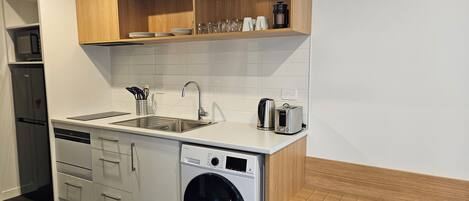 A compact kitchen with a built-in dishwasher, a sink, and a toaster.