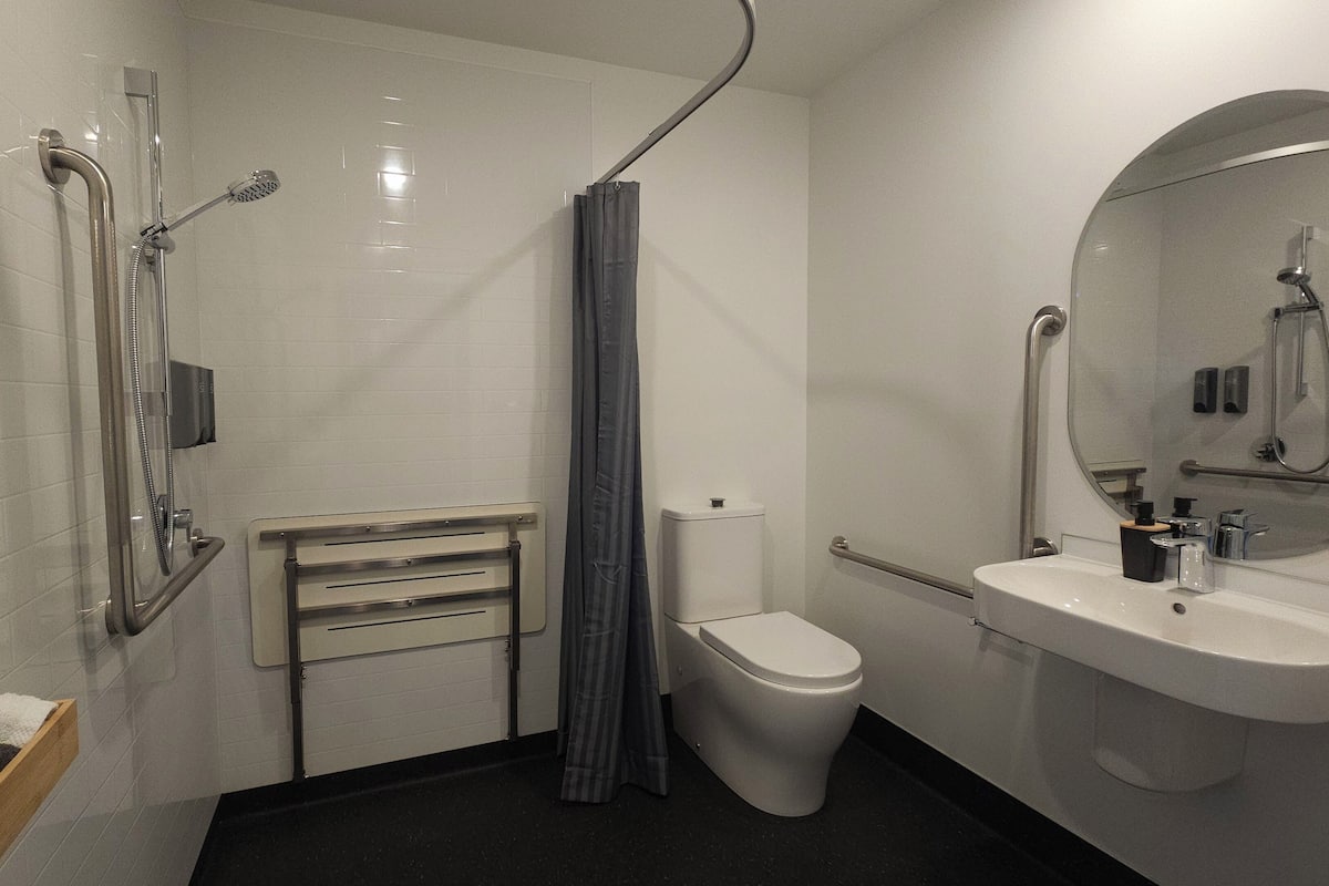 A modern bathroom with a shower, toilet, and sink.