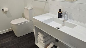 A modern bathroom with a white sink, toilet, and shower. - Alps Motel Apartment Twizel (Twizel)