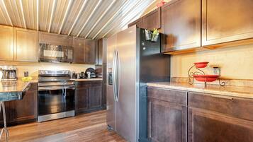 A modern kitchen with stainless steel appliances, wooden cabinets, and a wooden ceiling.