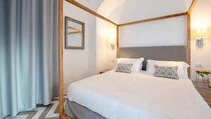 A modern hotel room with a large bed, a wooden headboard, and a mirror on the wall.