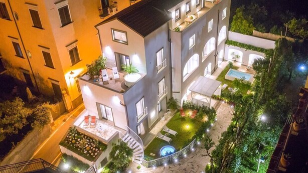 A multi-story building with a rooftop terrace, a swimming pool, and a landscaped garden.