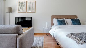 A modern hotel room with a bed, a TV, a sofa, and two framed artworks on the wall. - Blueground | Breite, elev, washer, balcony (Basel)