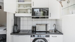 A compact kitchen with a microwave, toaster, sink, and washing machine. - Blueground | Breite, elev, washer, balcony (Basel)