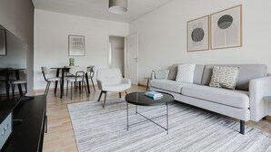 Ein modernes Wohnzimmer mit einem grauen Sofa, einem Couchtisch und einem Essbereich mit Stühlen und einem Tisch.