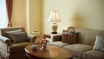 A cozy living room with a sofa, a coffee table, a lamp, and a suitcase.