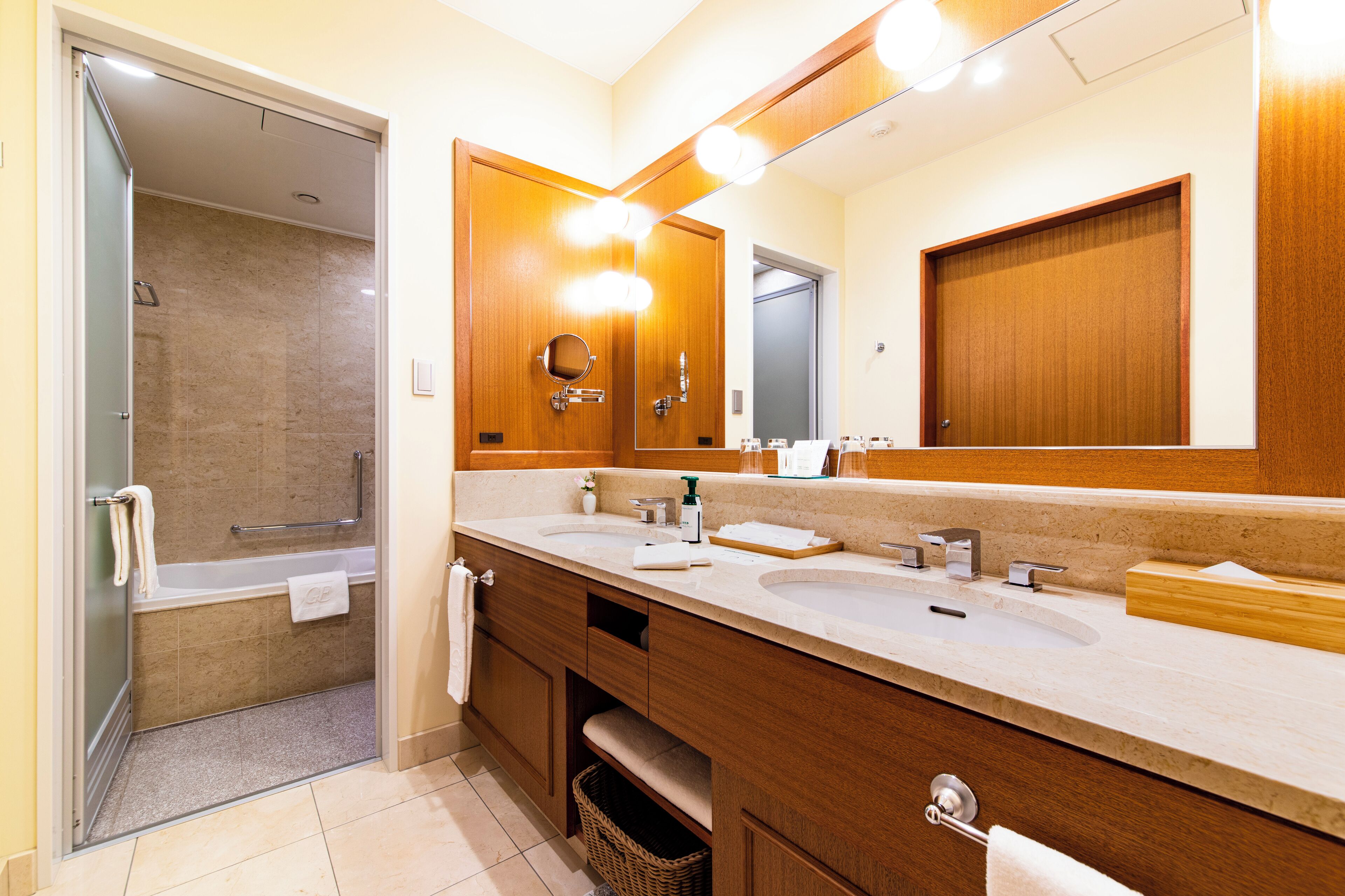 Un bagno moderno con due lavabi, uno specchio grande e una zona doccia.