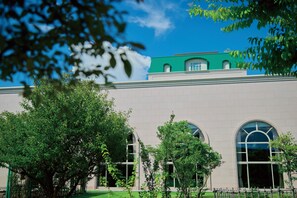 A building with a green roof, large arched windows, and surrounded by trees. - Grand Empire Hotel (Oonojo)