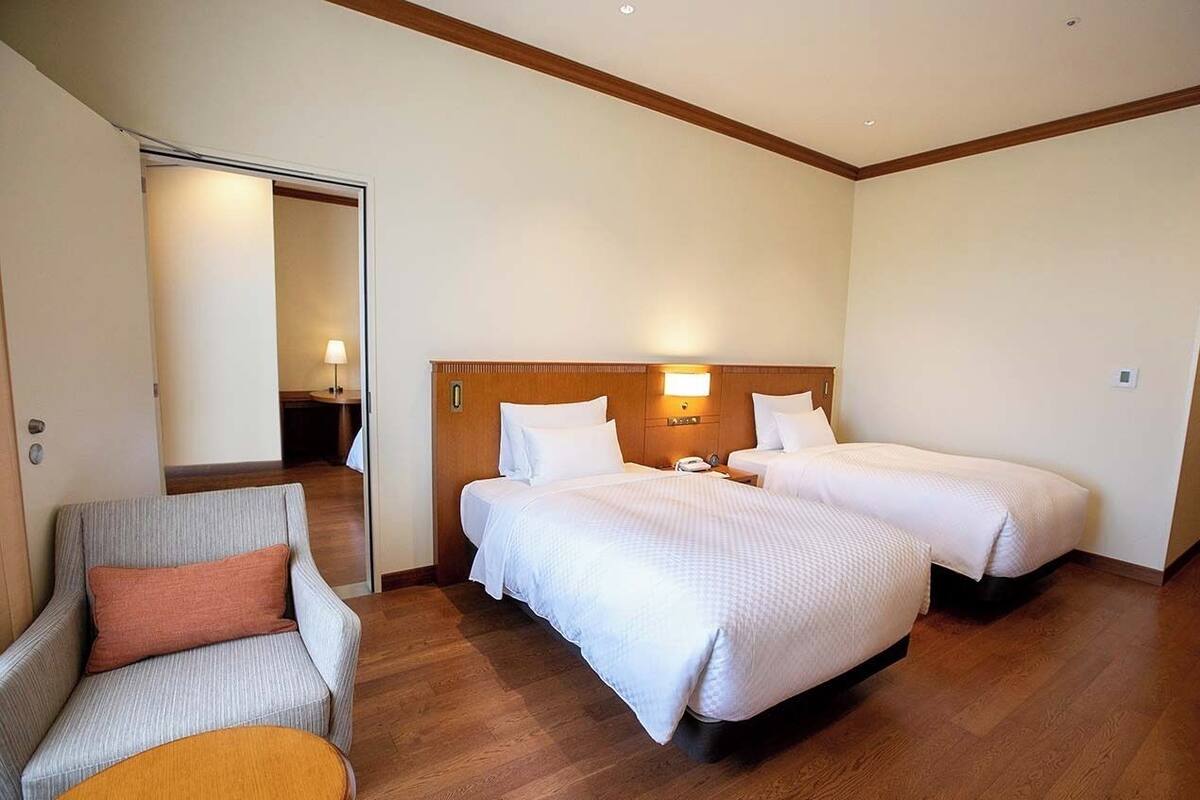Een hotelkamer met twee bedden, een stoel, een nachtkastje en een lamp.