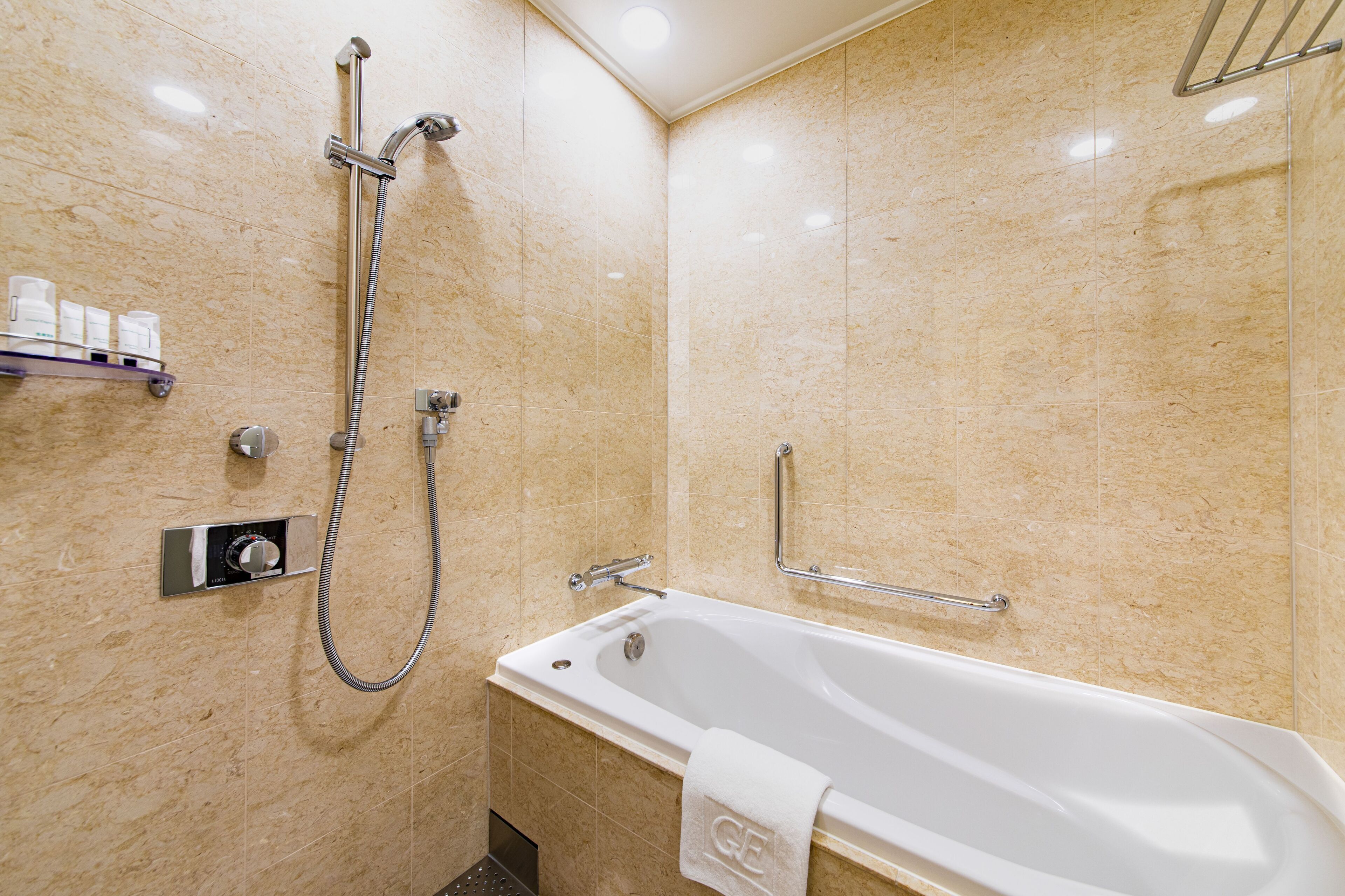 A modern bathroom with a bathtub, a handheld showerhead, and a wall-mounted control panel.