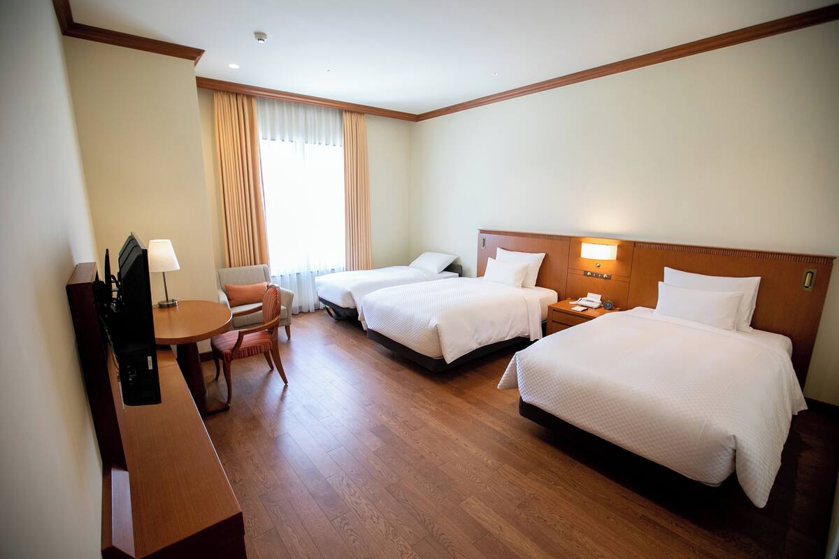 Een hotelkamer met twee bedden, een bureau, een stoel en een televisie.