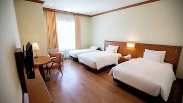 A hotel room with two beds, a desk, a chair, and a TV.