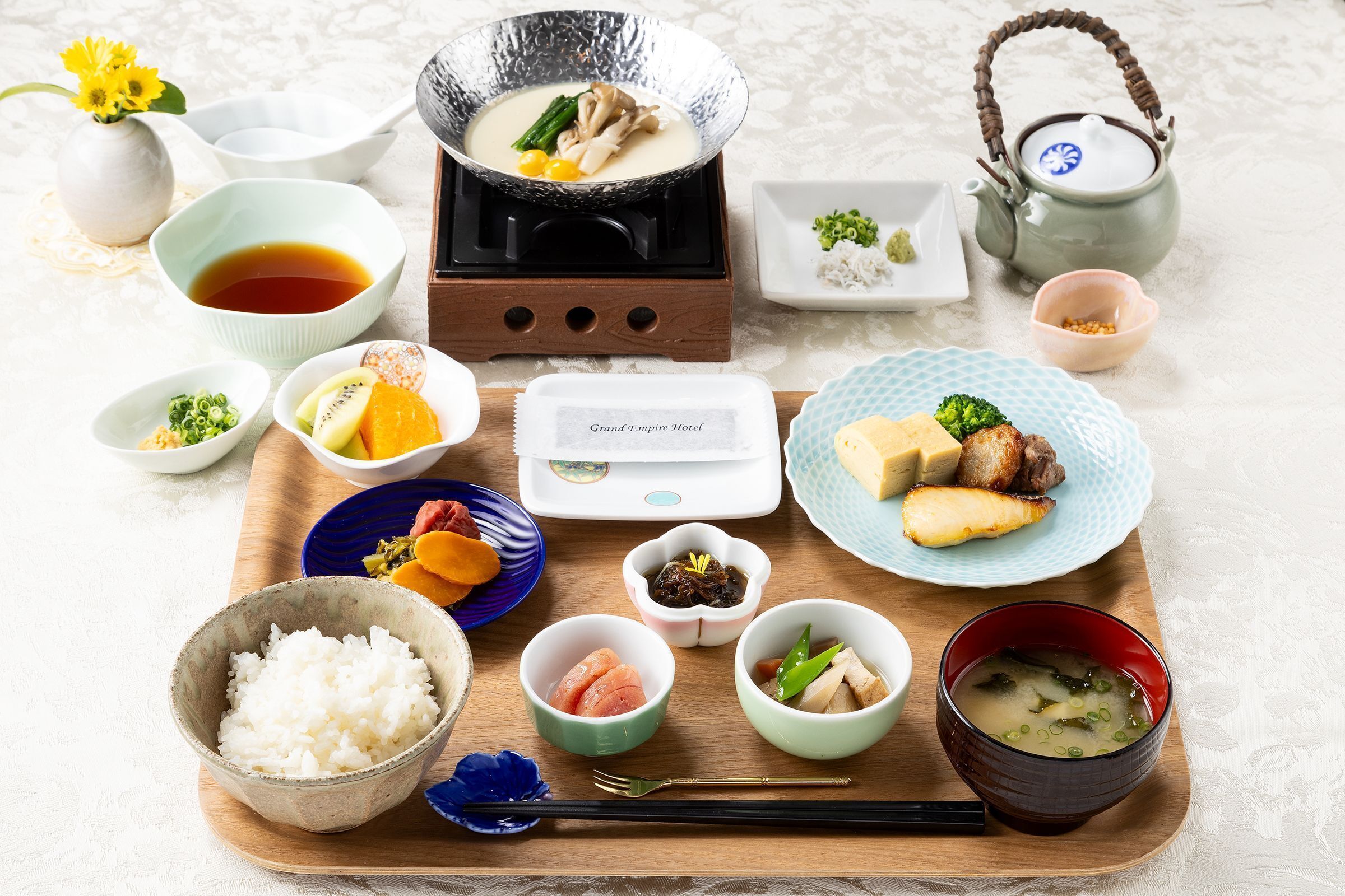 Una comida tradicional japonesa con diversos platos, como arroz, sopa y carne, dispuesta sobre una bandeja de madera.