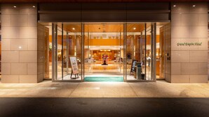 L’entrée du Grand Empire Hotel se distingue par ses portes en verre, un atrium central et un comptoir d’accueil.