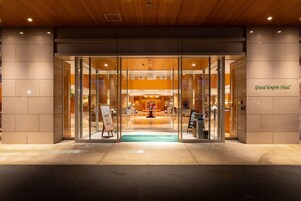 The Grand Empire Hotel entrance with glass doors, a central atrium, and a reception desk.