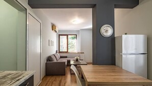 A compact living space with a kitchenette, a dining area, and a seating area with a sofa and a table. - Karavelov Top Center Apartment (Varna)