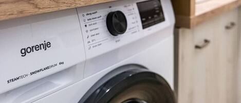A front view of a white washing machine with a wooden countertop above it.