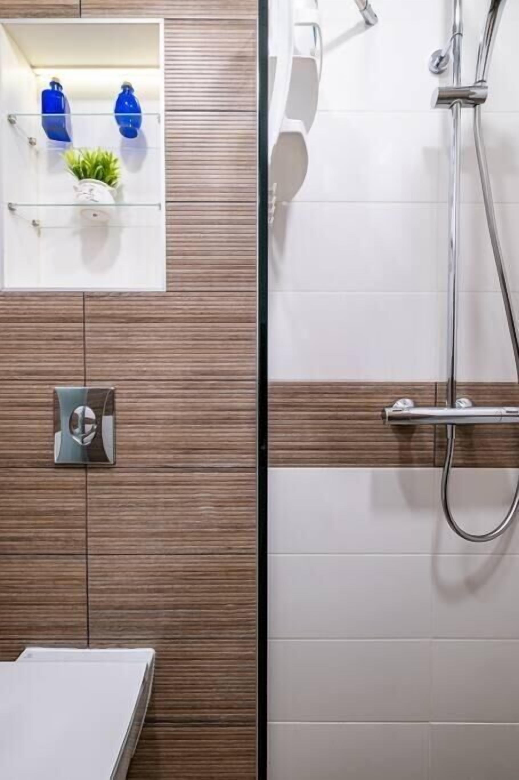 Ein modernes Badezimmer mit einer Wand aus Holzpaneelen, einer Glasablage für Pflegeprodukte und einer Duschkabine.