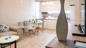 En moderne stue med sofa, sofabord og et spiseområde med stole. En vase står på et træbord.