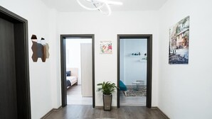 A hallway with a wooden floor, a round rug, a potted plant, and a painting on the wall. - Black Sea 2bdrm Central Apartment (Varna)