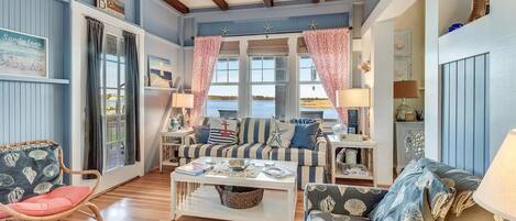 A coastal-themed living room with a large window, striped furniture, and nautical decor.