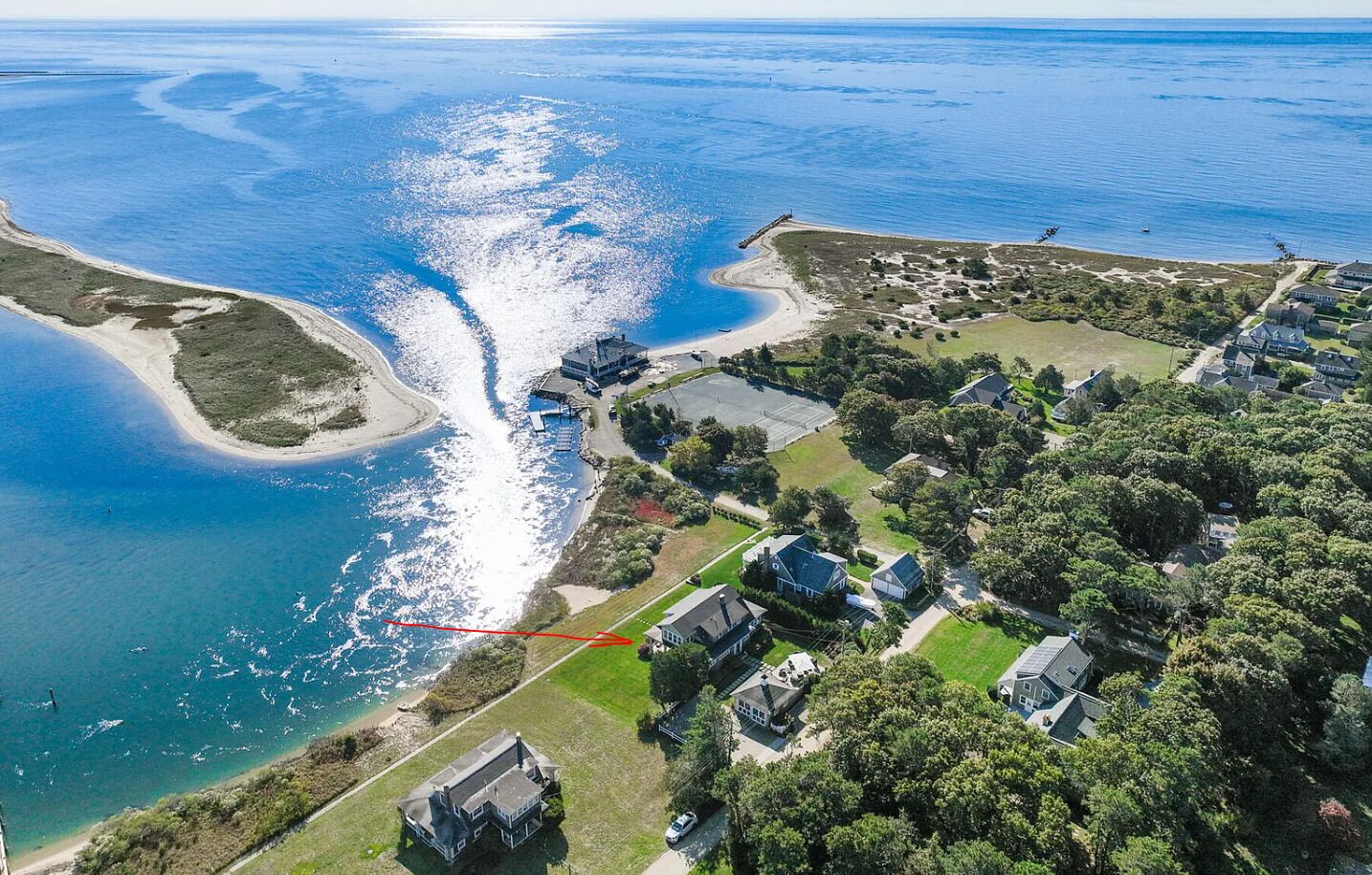 Luchtbeeld van een kustgebied met huizen, een strand en een pier.