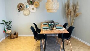 Un comedor con una mesa de madera, sillas negras y una lámpara colgante de ratán.