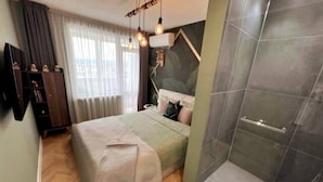 Un dormitorio con cama, mesita de noche, televisor y zona de ducha.