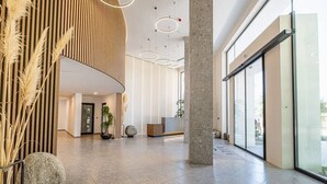 Een ruime lobby met een modern ontwerp, met een receptiebalie, een grote pilaar en een glazen wand met uitzicht.
