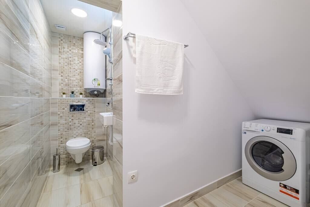 A bathroom with a toilet, sink, towel rack, and a washing machine.