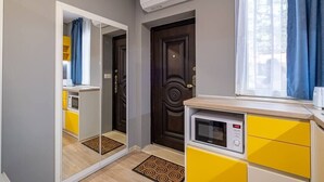 Une cuisine compacte équipée d’un four à micro-ondes, d’un petit réfrigérateur et d’une fenêtre avec des rideaux.