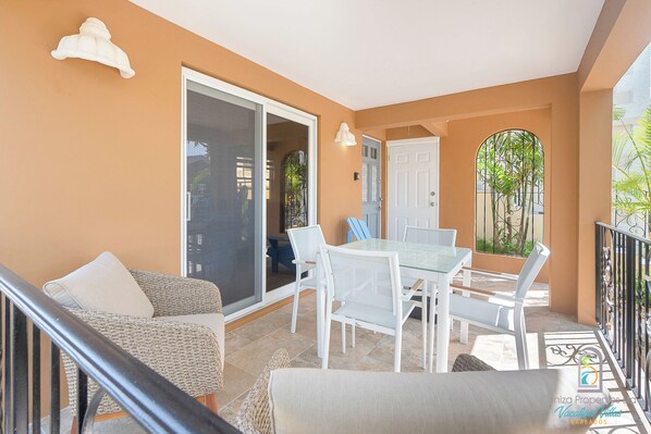 Ein Balkon mit Glastür, weißen Möbeln und Blick ins Freie.