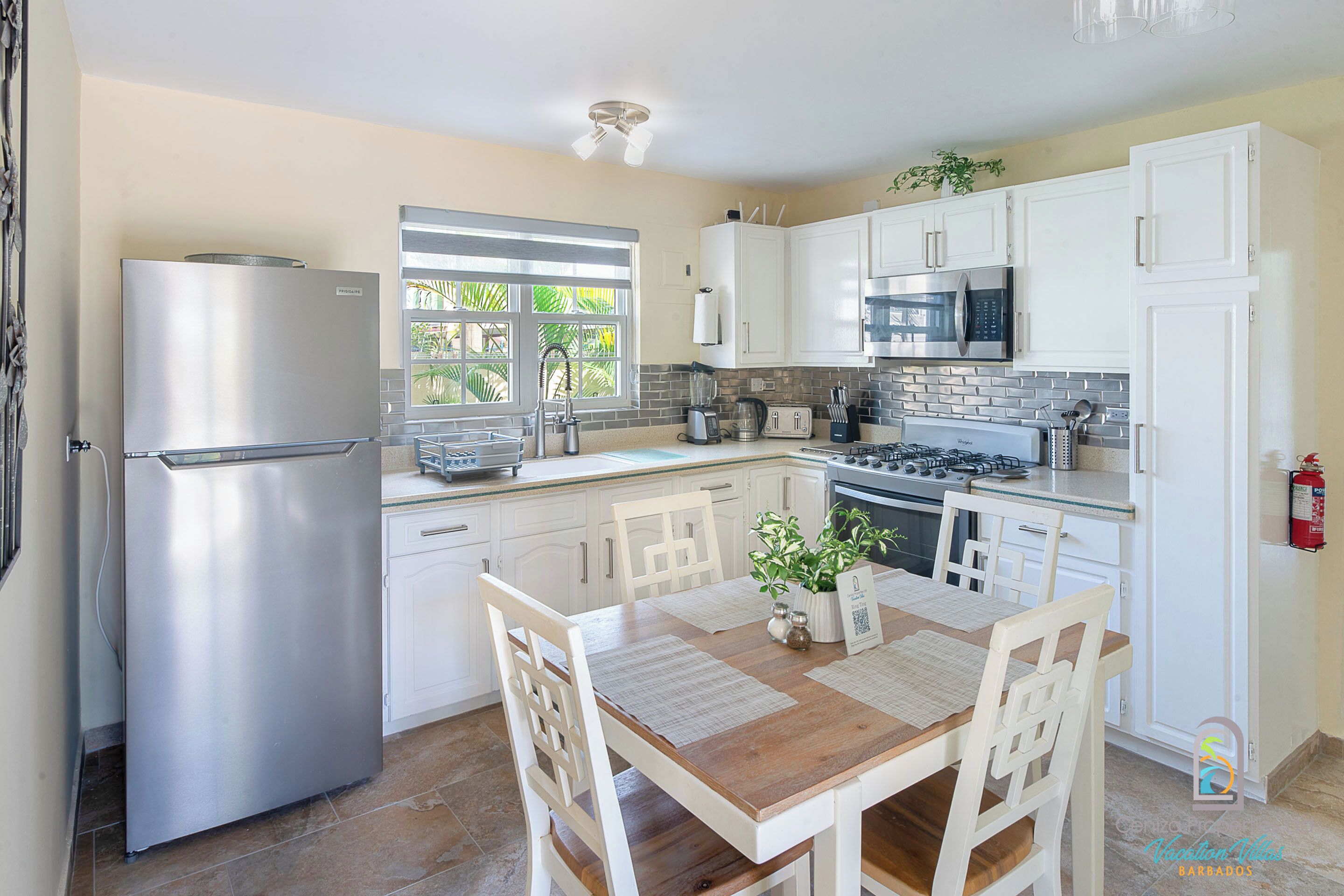 A modern kitchen with white cabinets, stainless steel appliances, and a wooden dining table.