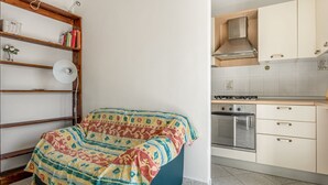 Ein Schlafzimmer mit einem Bett, einer Holzregal und einer Küche mit Schränken und einem Herd.