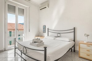 Une chambre à coucher avec un lit, une table de chevet, une lampe et une vue sur l’extérieur.