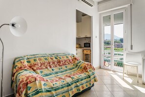 A room with a bed, a small table, a TV, and a balcony with a view.