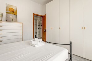 A bedroom with a bed, a dresser, a wardrobe, and a door leading to a bathroom.