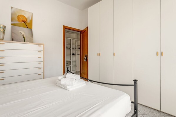 A bedroom with a bed, a dresser, a wardrobe, and a door leading to a bathroom.