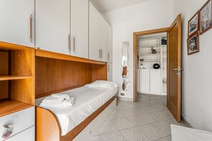 Un dormitorio con cama, armario de madera y una pequeña alacena.