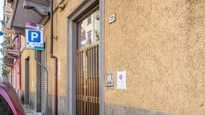 Un bâtiment avec un panneau indiquant un parking, une entrée fermée par un portail et un panneau affichant un numéro.